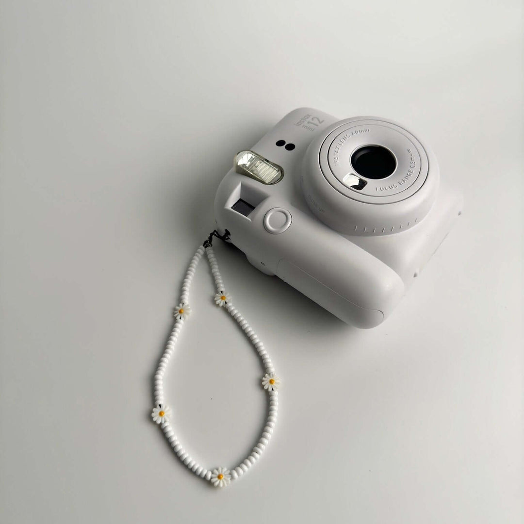 Image shows the Hatossa daisy phone strap on the instax mini polaroid.