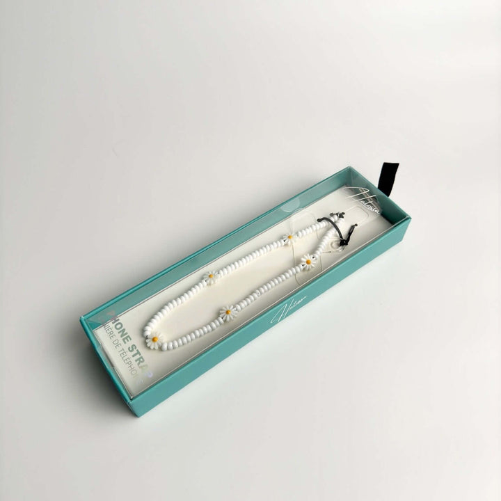 Image shows the packaged Hatossa Daisy phone strap, phone charm, with the universal lanyard holder that can be used with any device, ebook, airpods