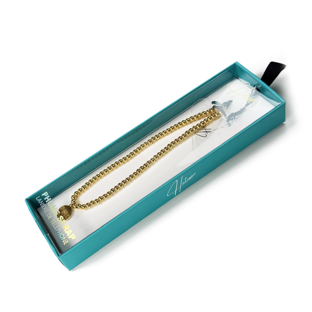 Golden Hatossa phone charm inside a blue Hatossa gift ready box.